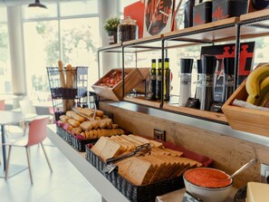 Un bufé de desayuno con pan, bollería, salsas y diversas bebidas.