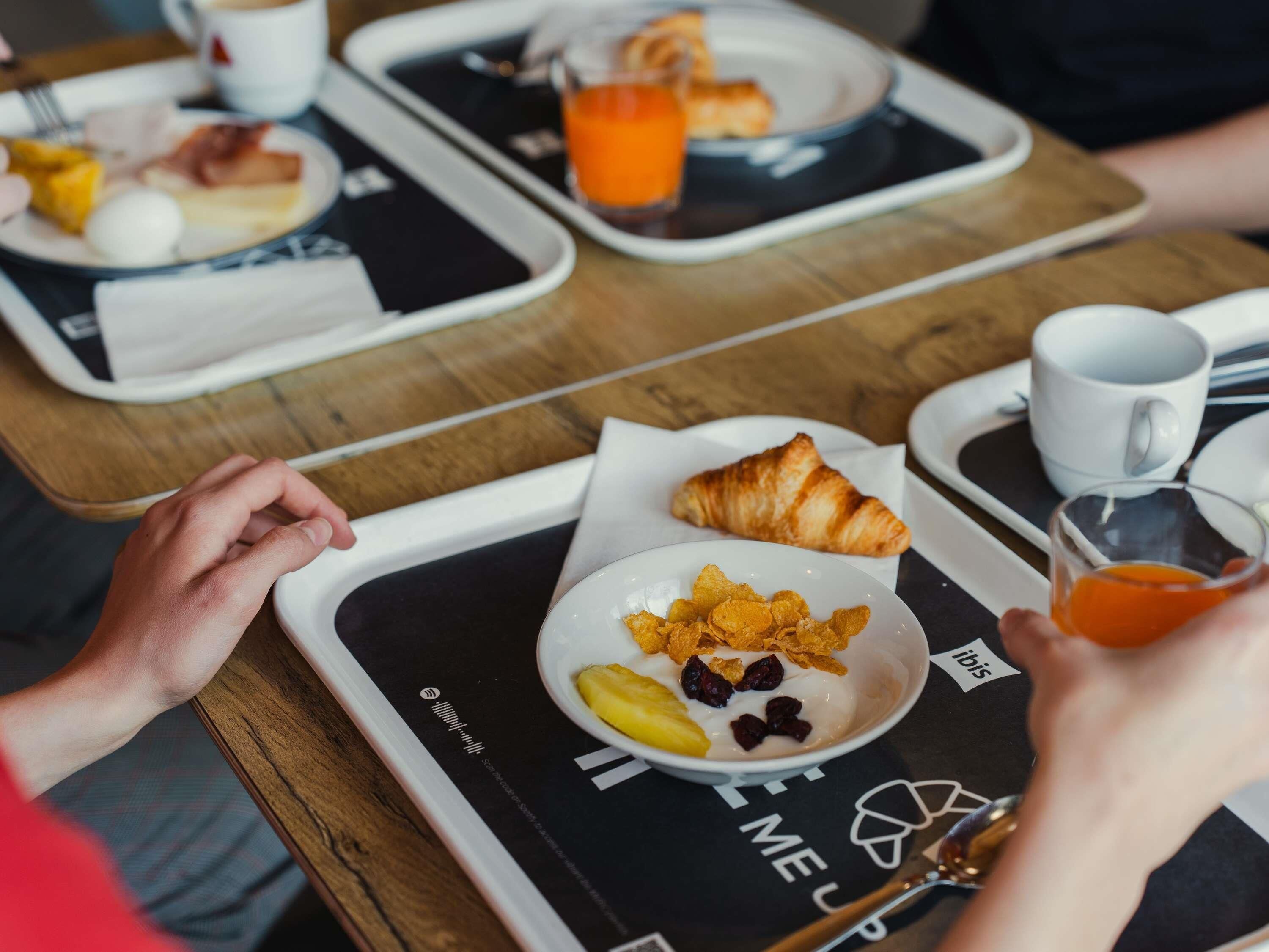 A breakfast setting with trays, croissants, cereal, and juice.