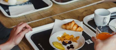 Desayuno con bandejas, cruasanes, cereales y jugo.