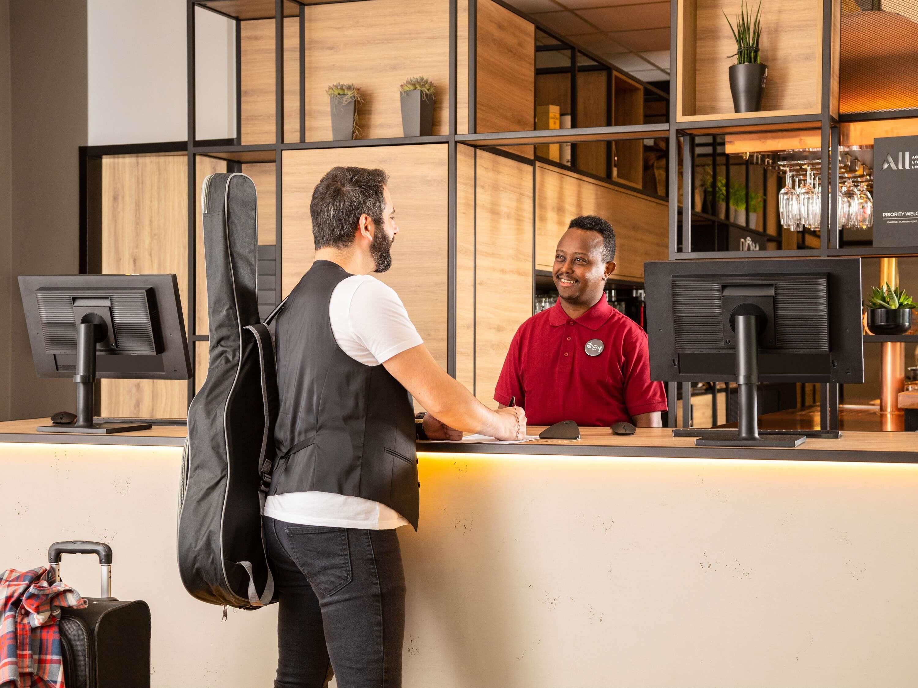 Una recepción con dos monitores, interior de madera y una planta en maceta.
