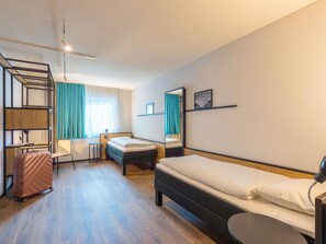 A hotel room with a bed, a desk, a chair, a suitcase, and a bunk bed. - ibis Dortmund City (Dortmund)