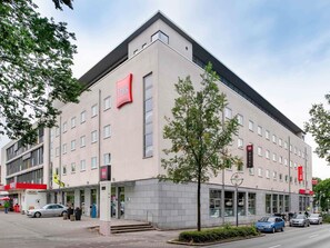 Un hotel moderno con fachada plana, varias ventanas y el llamativo logotipo rojo de ibis.