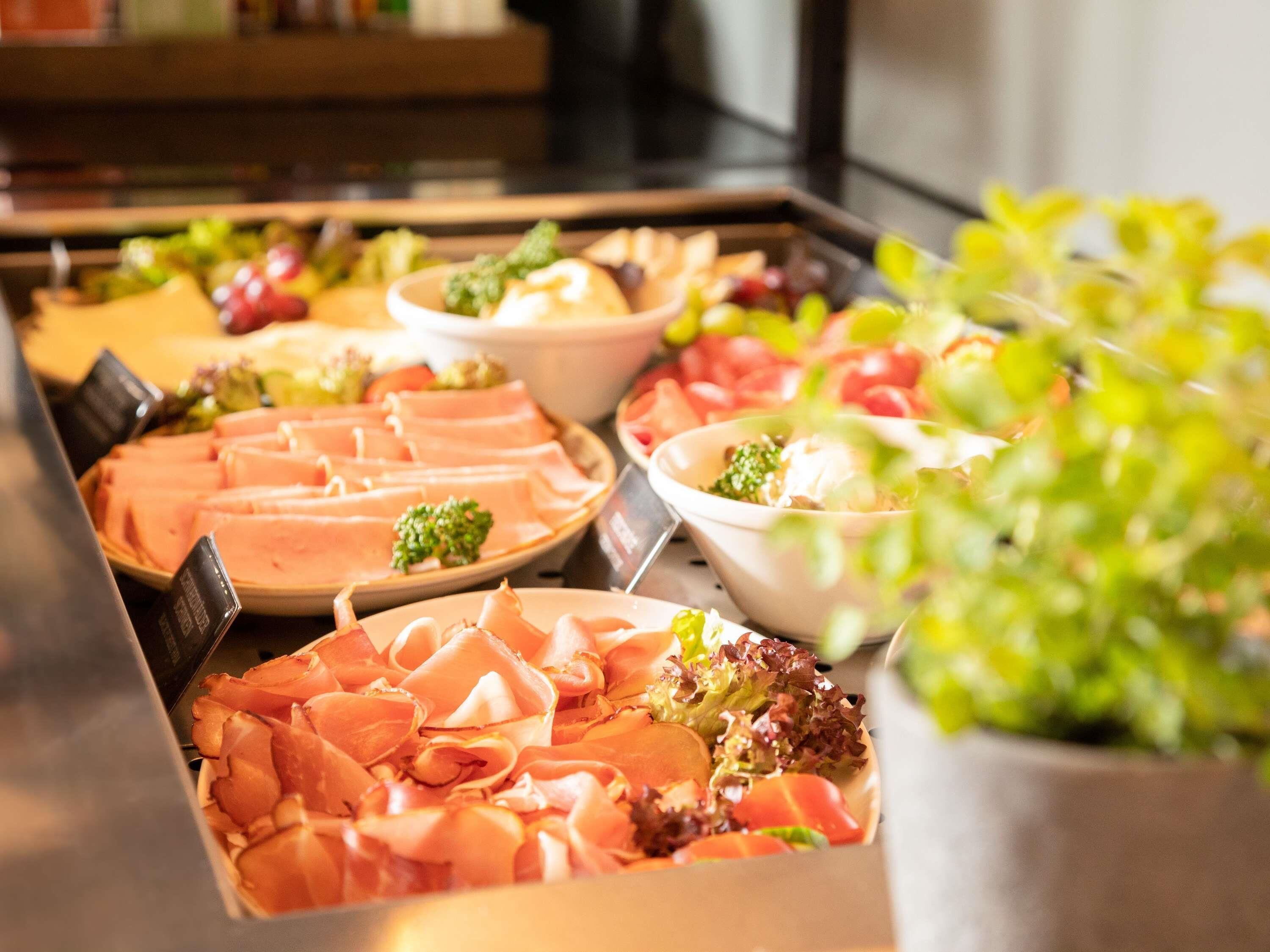 Un buffet proposant une variété de plats, notamment des viandes et des salades.