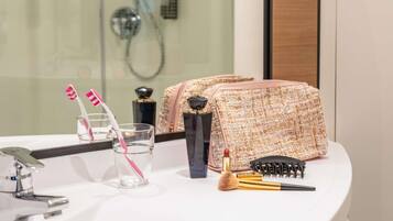 Un baño con cabina de ducha de vidrio, un lavamanos blanco, un espejo y una bolsa de artículos de aseo sobre el mostrador.