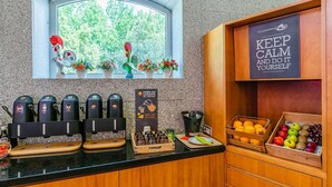 A kitchen counter with coffee machines, a juicer, and a fruit display. - Ibis Guimaraes (Guimarães)