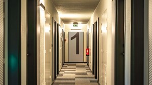 A hotel hallway with a checkered floor, doors on both sides, and a fire extinguisher mounted on the wall. - Ibis Guimaraes (Guimarães)