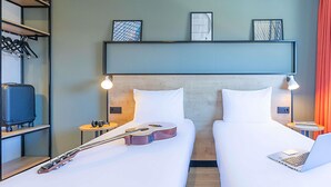 A hotel room with two beds, a guitar, a suitcase, and a laptop. - Ibis Guimaraes (Guimarães)