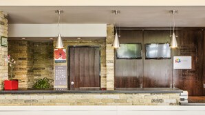 A reception area with a stone wall, wooden doors, and hanging pendant lights. - Ibis Guimaraes (Guimarães)