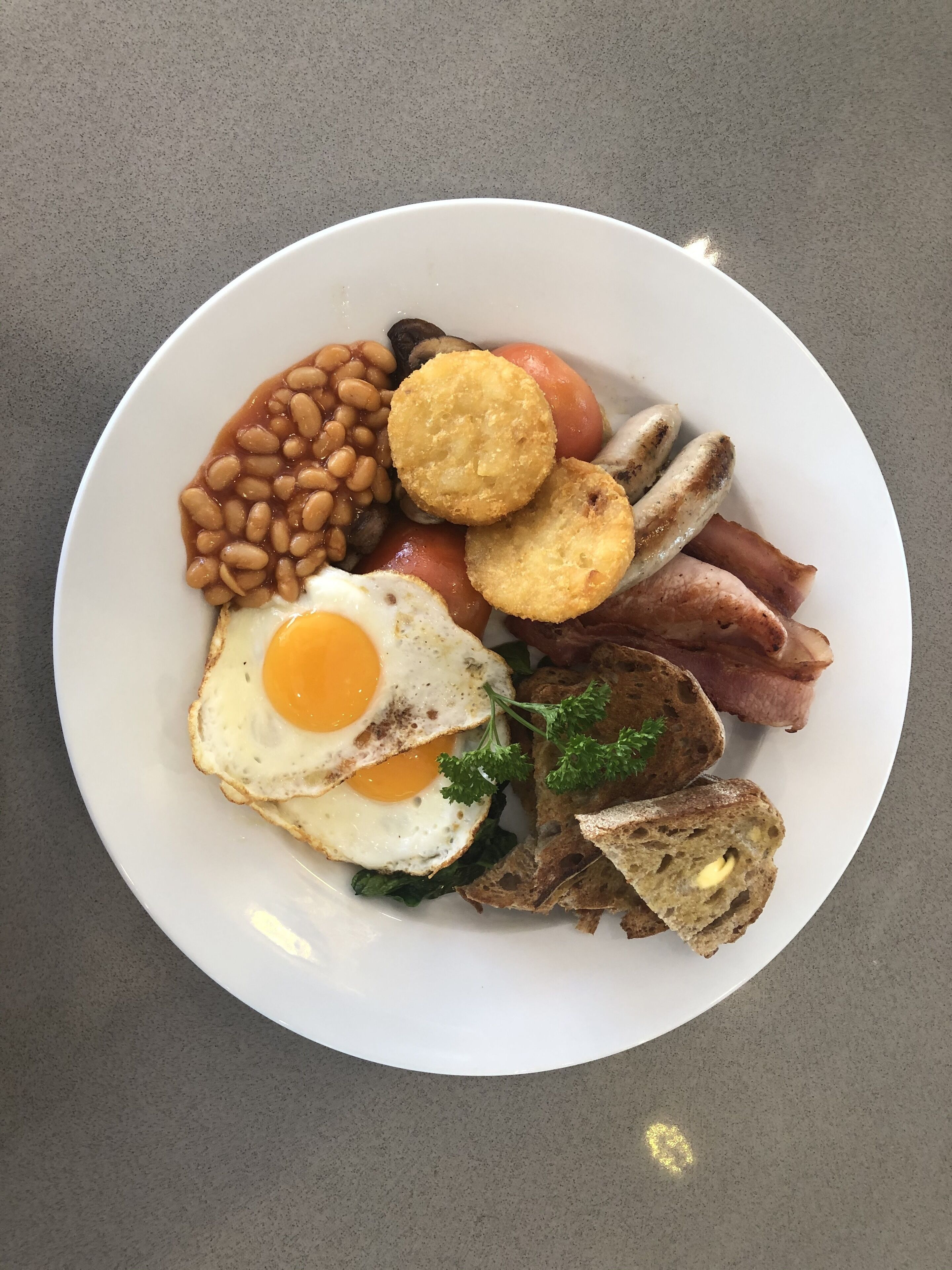 A plate of breakfast food including eggs, beans, bacon, and toast.