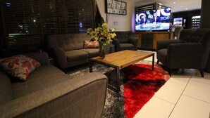 Una sala de estar moderna con un sofá, sillones, una mesa de centro y un televisor.