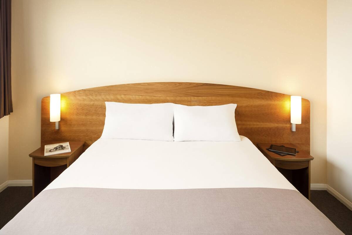 Ein Hotelzimmer mit einem großen Bett, zwei Nachttischen und Wandleuchten.