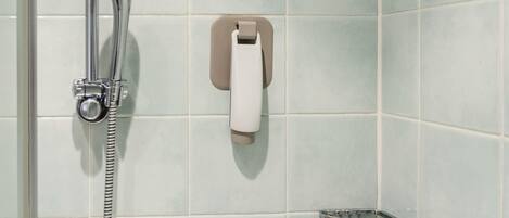 Un baño con ducha, toallero y dispensador de jabón.