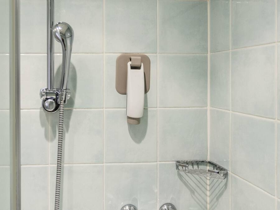 A bathroom with a shower, a towel rack, and a soap dispenser.