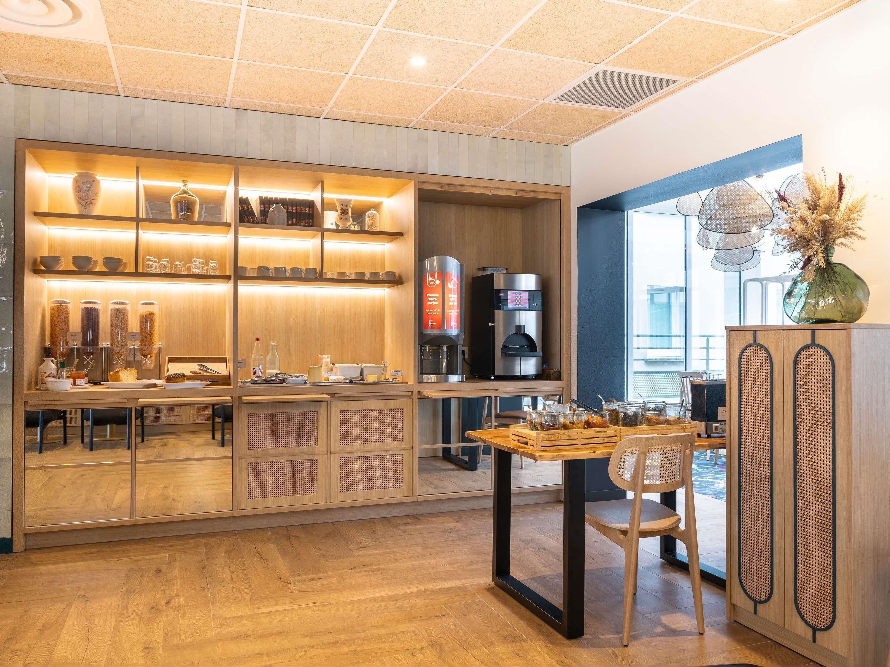A modern cafe interior with a coffee machine, seating area, and a wooden counter with various items.