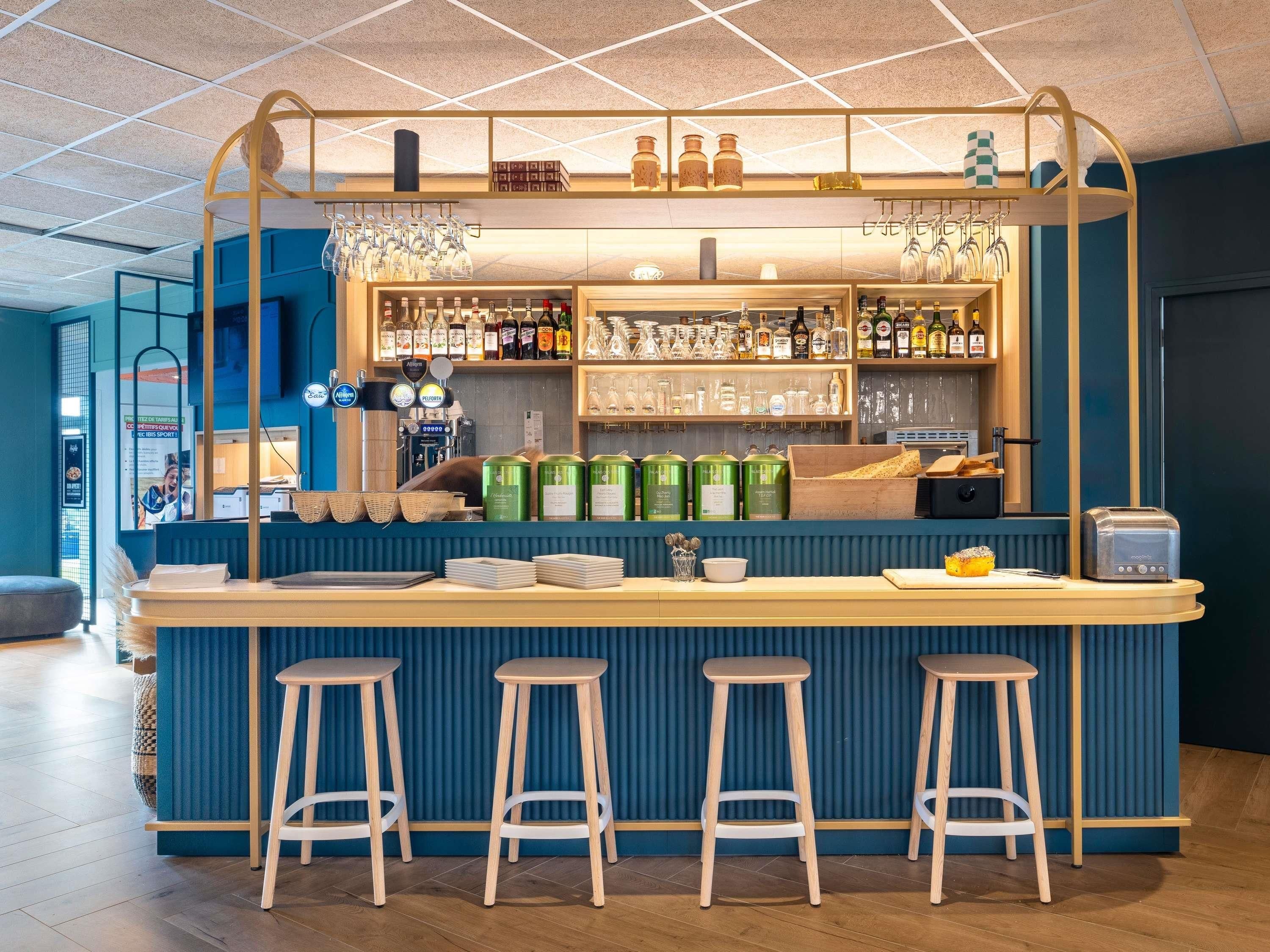 A bar area with stools, a counter, and shelves stocked with bottles and glasses.