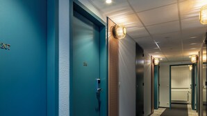 A hallway with teal-colored doors, numbered 207 and 206, leading to rooms. - ibis Styles Pontivy Centre Bretagne (Pontivy)
