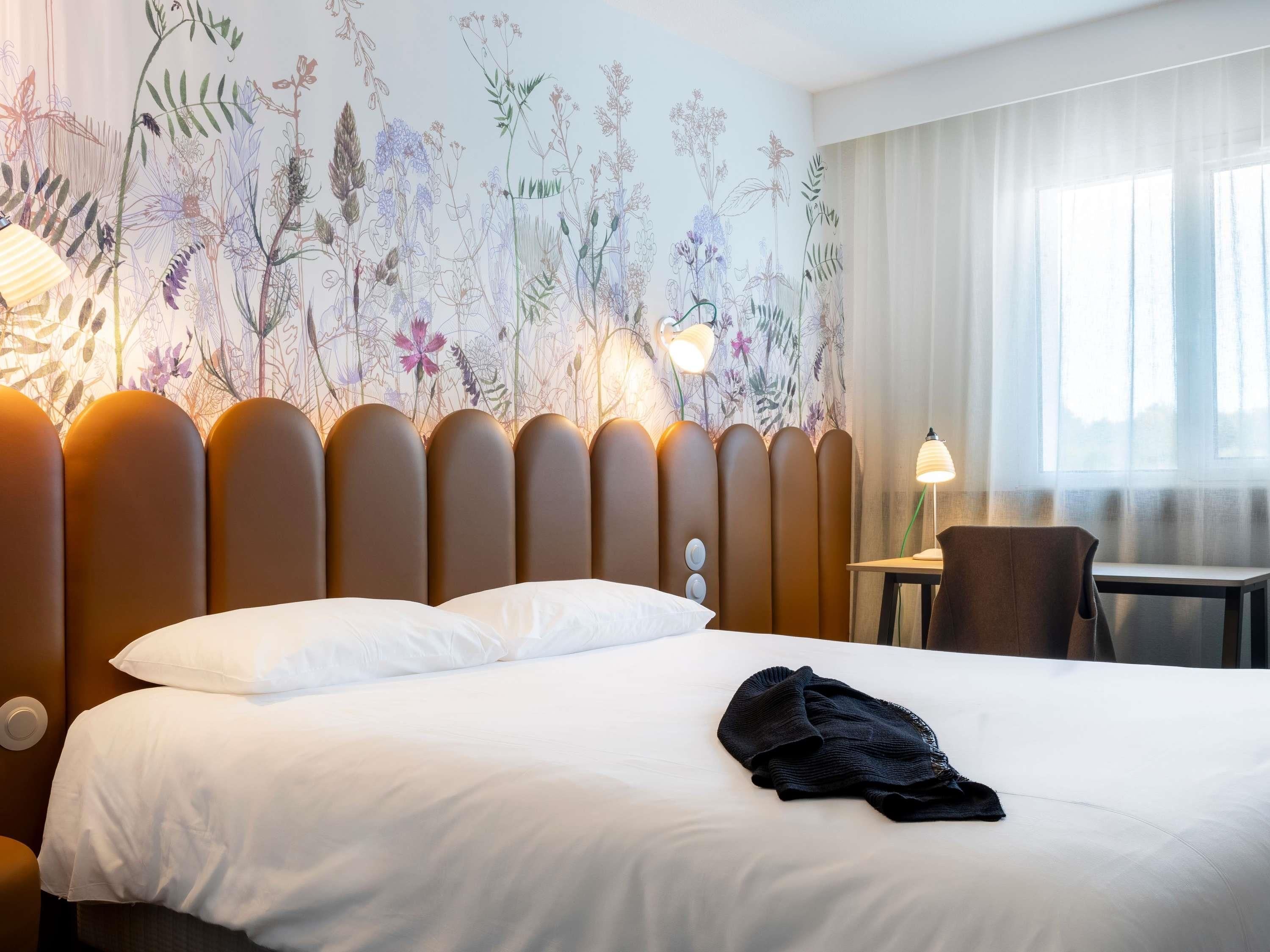 A hotel room with a bed, a desk, and a chair.