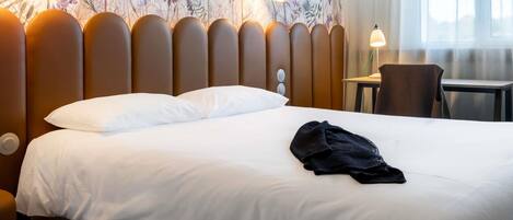 A hotel room with a bed, a desk, and a chair.