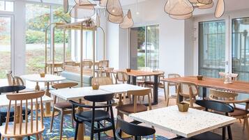 A restaurant with tables and chairs, a ceiling with air vents, and a colorful floral carpet.