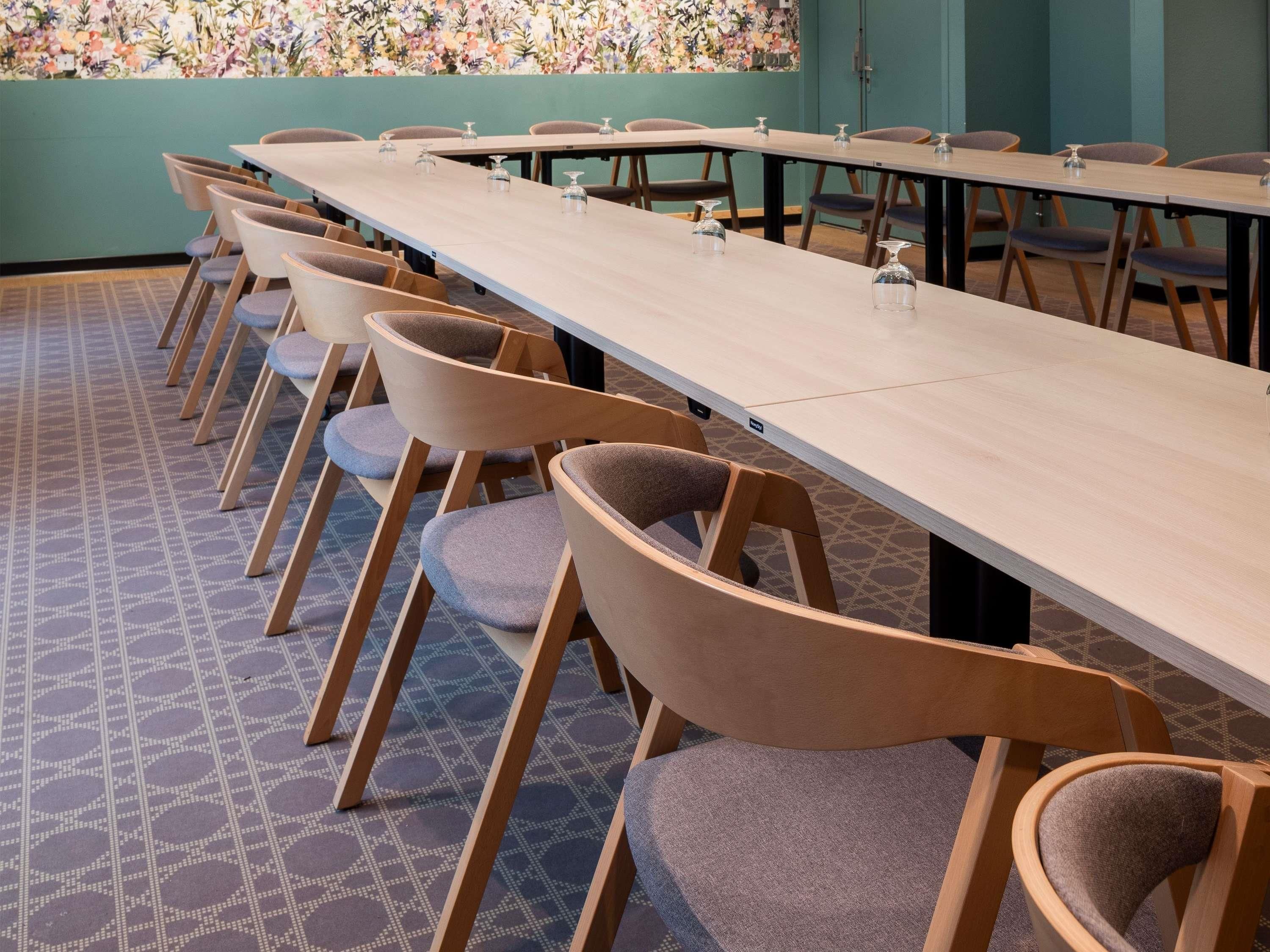 A conference room with a long table and chairs, patterned carpet, and a floral wall mural.