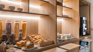 A modern breakfast bar with a variety of food items, including pastries and cereals, and a coffee machine. - ibis Styles Pontivy Centre Bretagne (Pontivy)