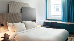 Una camera d'albergo con un letto grande, una scrivania e una finestra con tende.