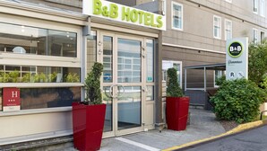 A B&B hotel entrance with a glass door, a signboard, and a welcome sign. - B&B HOTEL Paris Nord 2 CDG Aéroport (Roissy-en-France)