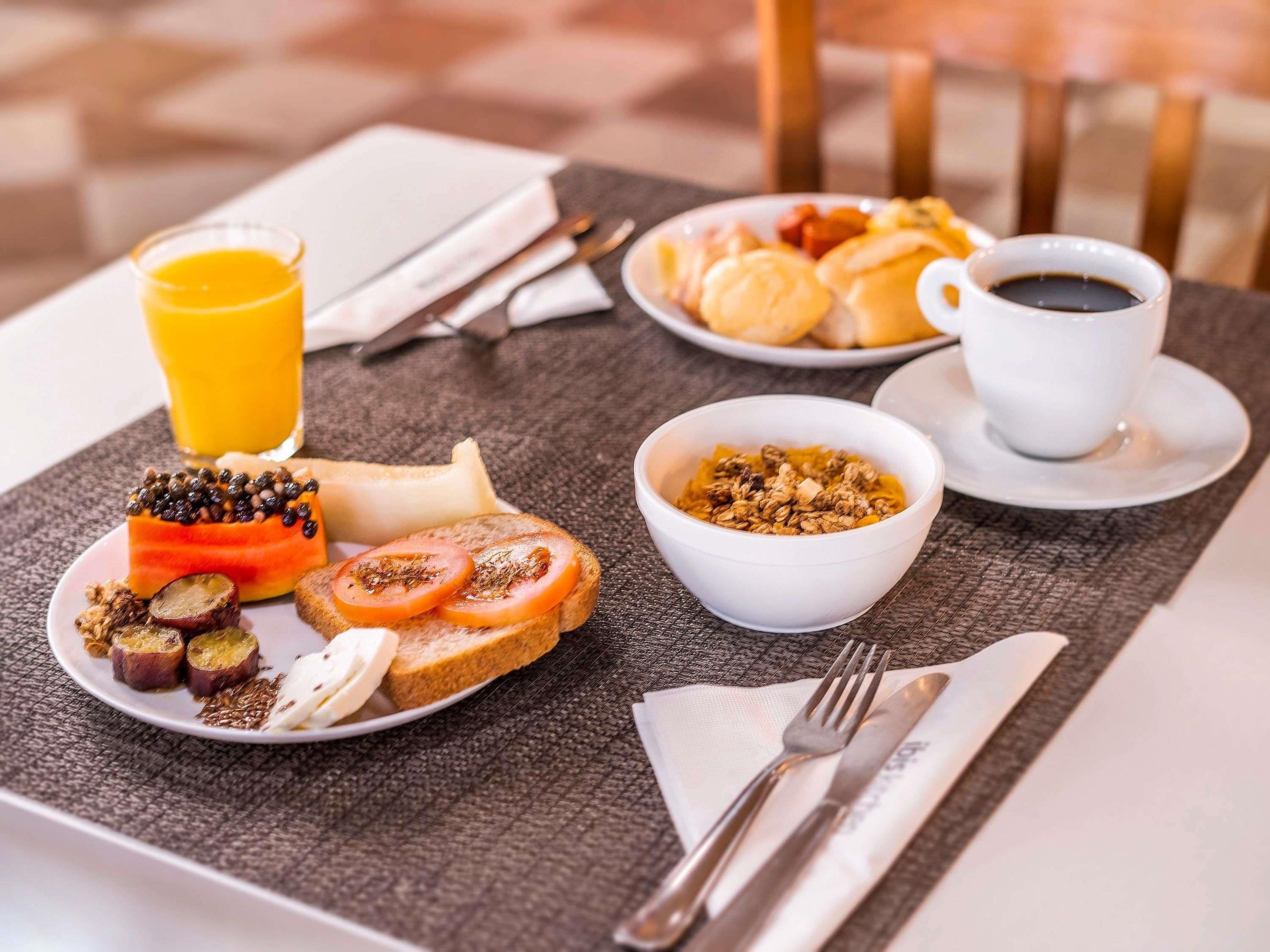 Una escena de desayuno con tostadas, tomates y un tazón de granola.