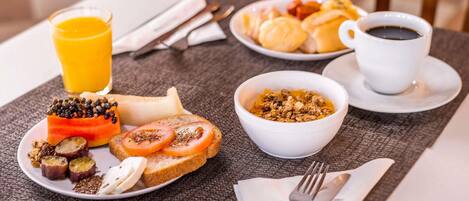 Una escena de desayuno con tostadas, tomates y un tazón de granola.