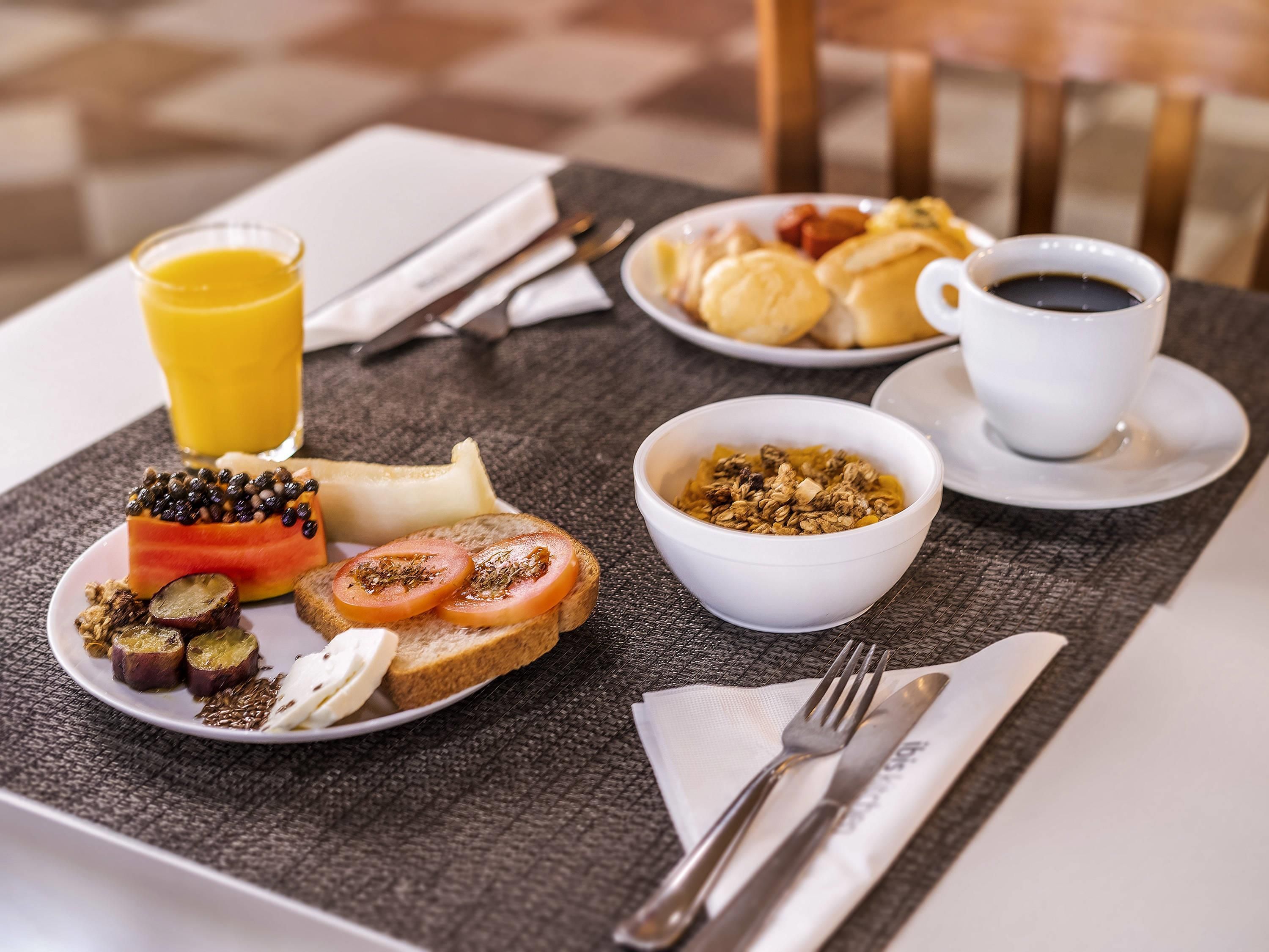 Ein Frühstückstisch mit Toast, Tomaten und einer Schüssel Granola.