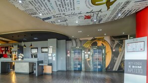 A modern hotel lobby with a reception desk, a circular ceiling design, and a sign that reads "BEM-VINDO E BOM APETITE!". - ibis Sorocaba (Sorocaba)