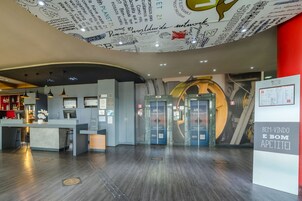 Un moderno vestíbulo de hotel con mostrador de recepción, diseño circular del techo y un cartel que dice "BEM-VINDO E BOM APETITE!".