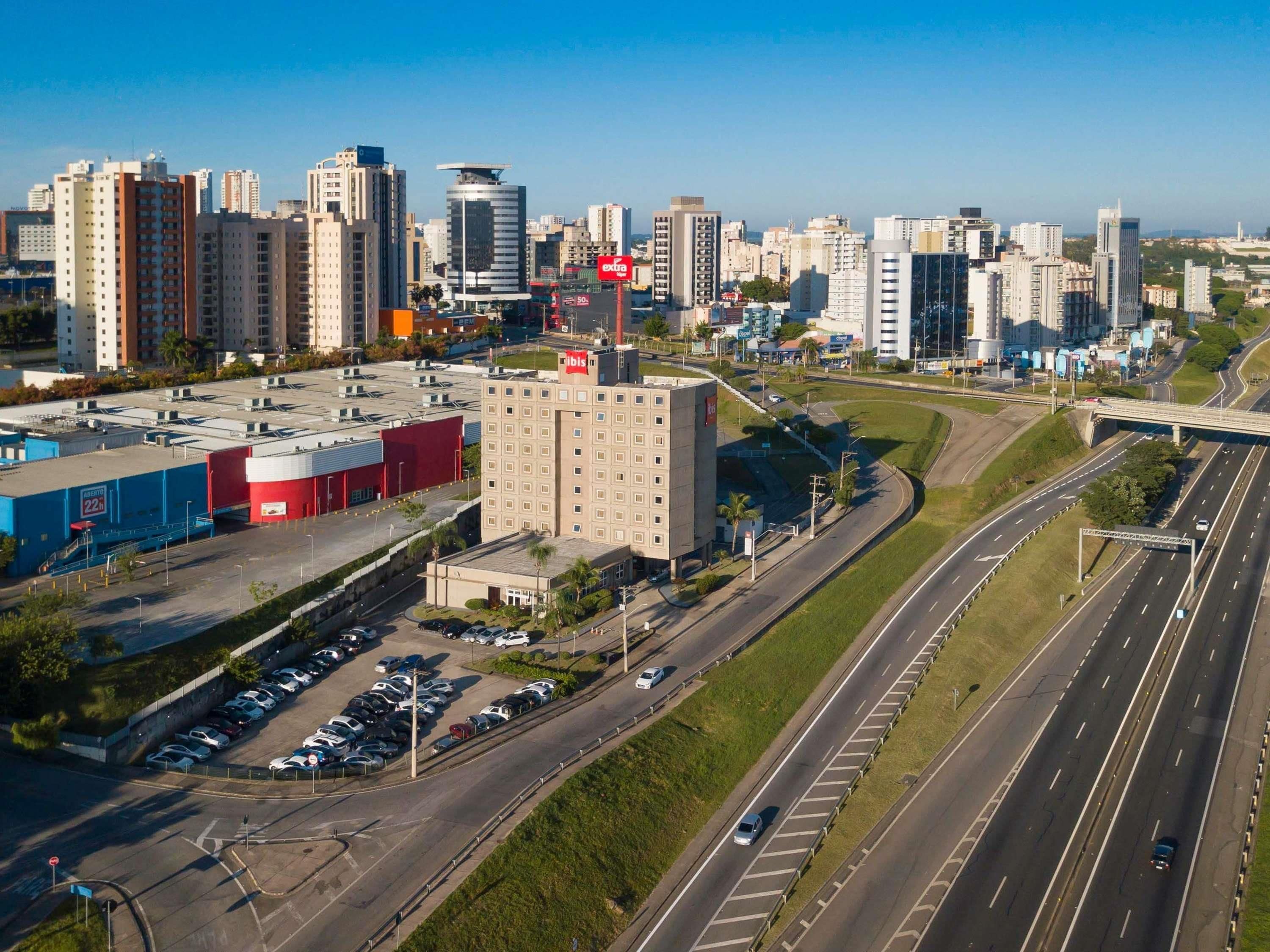 A multi-level parking structure adjacent to a highway with a hotel and office buildings in the background.