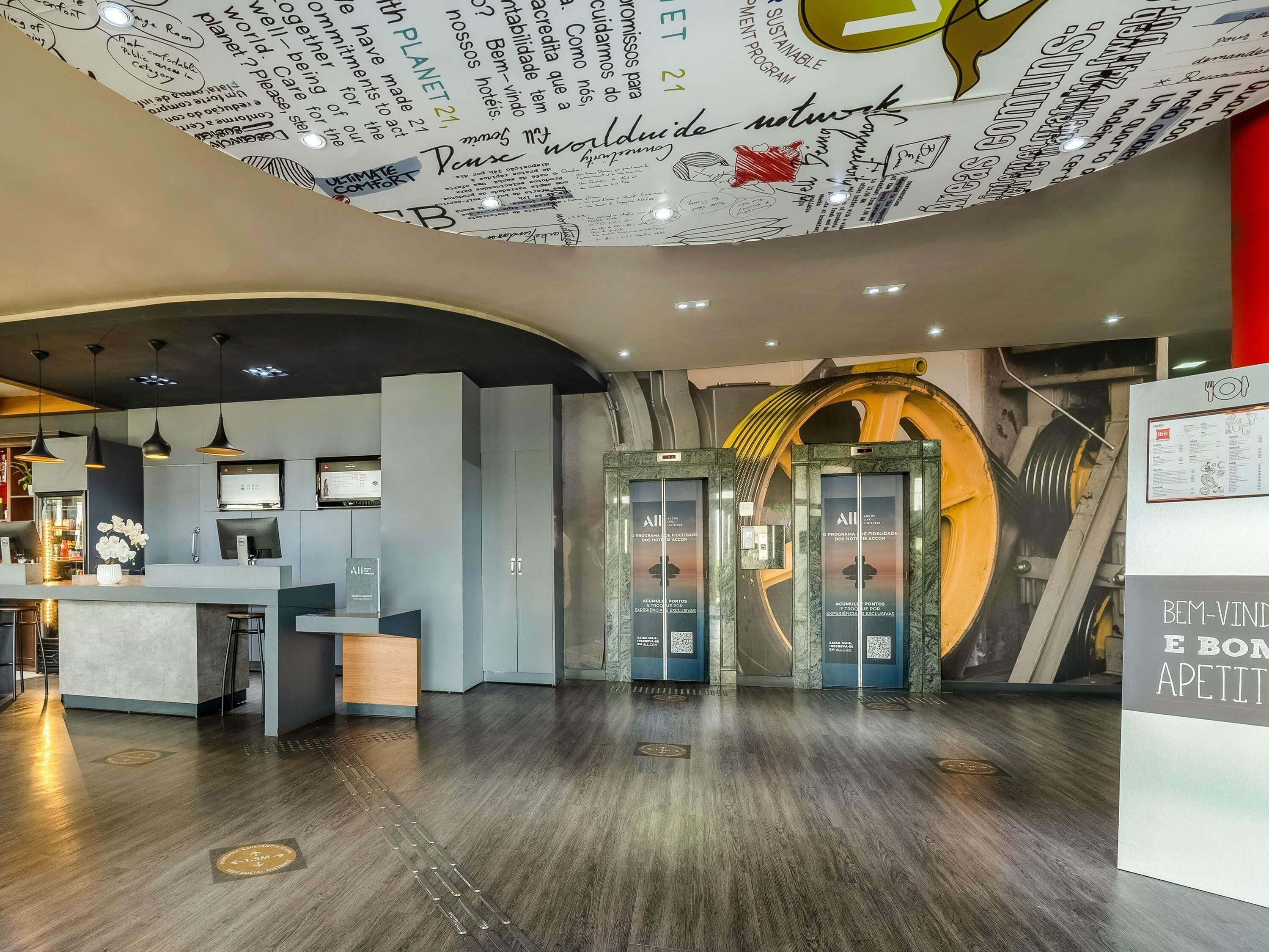 A hotel lobby with a reception desk, a seating area, and a circular ceiling design.