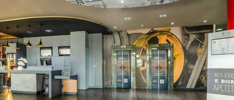 A hotel lobby with a reception desk, a seating area, and a circular ceiling design.