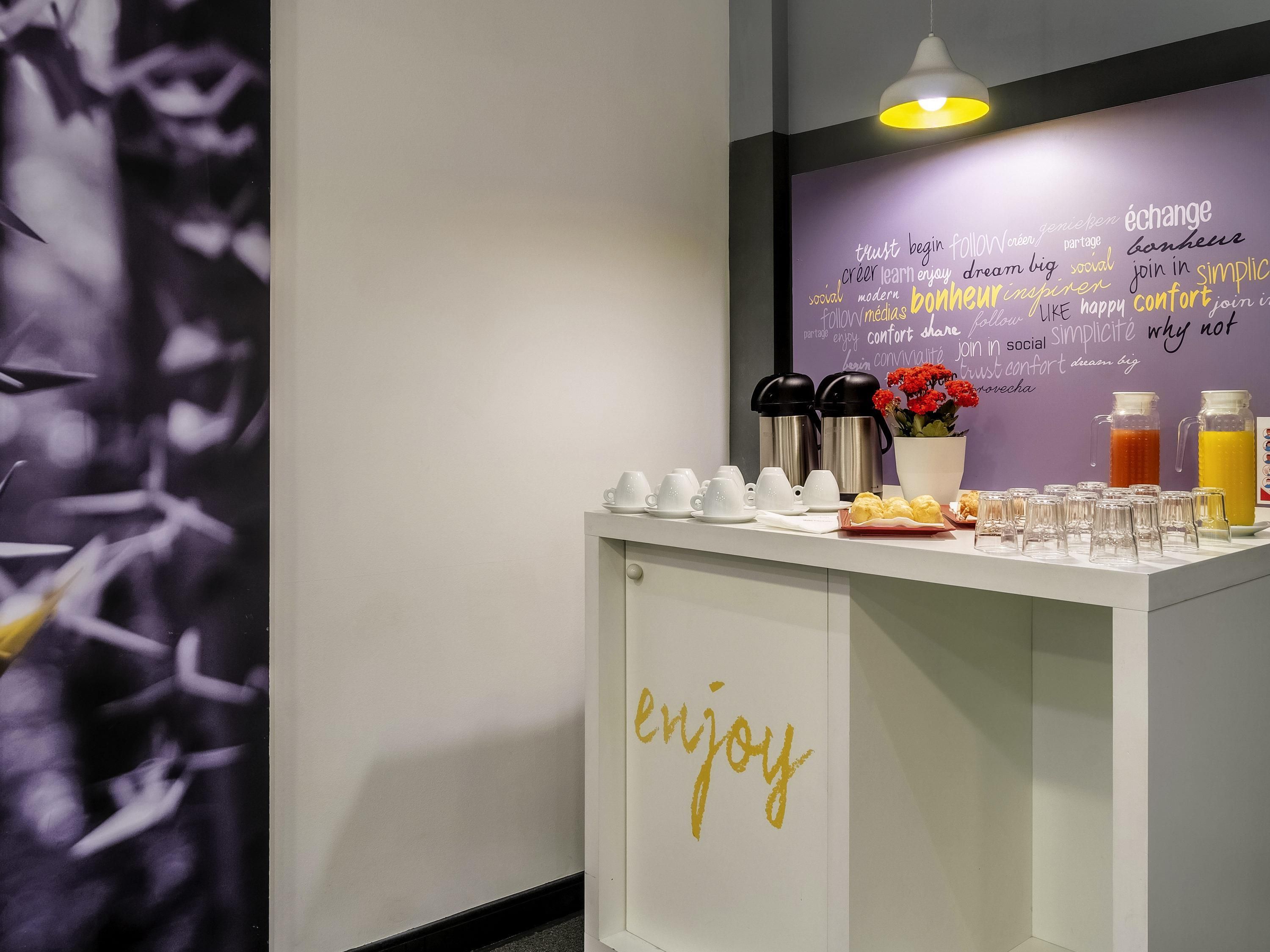 A breakfast bar with coffee makers, a fruit bowl, and a wall with motivational words.