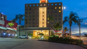 A multi-story hotel with a prominent "ibis" sign, a parking lot, and palm trees. - ibis Sorocaba (Sorocaba)