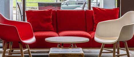 A red sofa with white chairs, a round table, and a wooden block with holes.