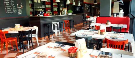 Un restaurante con mesas, sillas, un cartel de menú y una zona de bar.