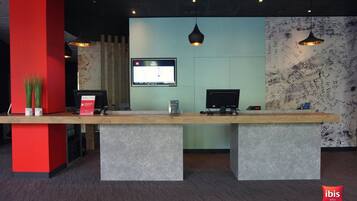 A reception desk with a computer, a television, and a sign.
