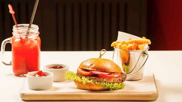 Comida con una hamburguesa, papas fritas y una bebida sobre una tabla de madera.