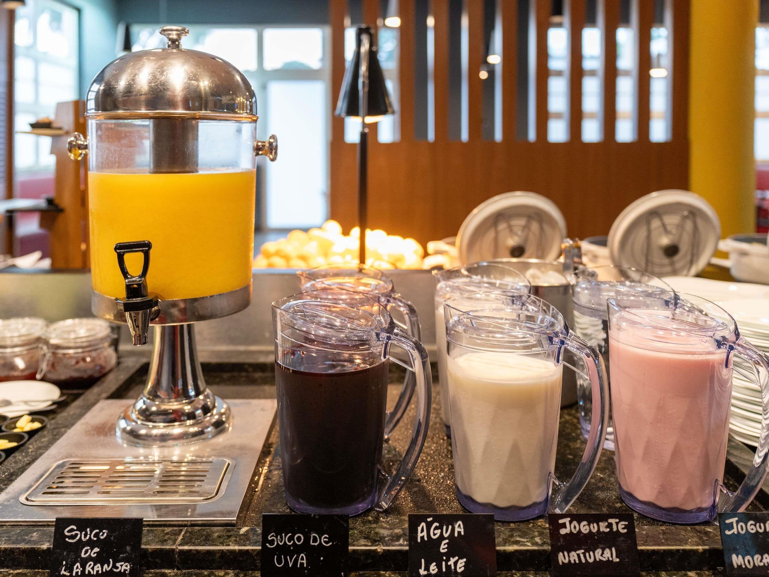 A beverage station with a juicer, pitchers of different drinks, and labels indicating the types of beverages available.