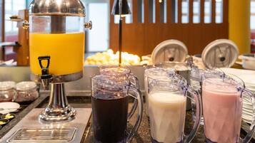 A beverage station with a juicer, pitchers of different drinks, and labels indicating the types of beverages available.