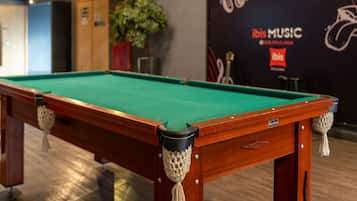 Ein Billardtisch mit grüner Spielvliesdecke, Holzbeinen und einer seilumwickelten Ecke.