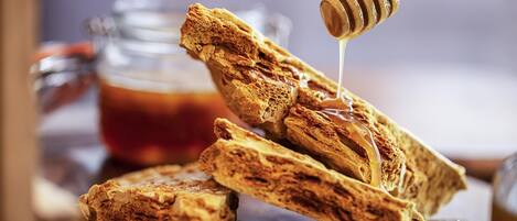 A close-up of honey being drizzled over a stack of bread.