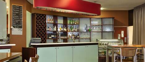 A bar area with a counter, shelves of bottles, and stools.