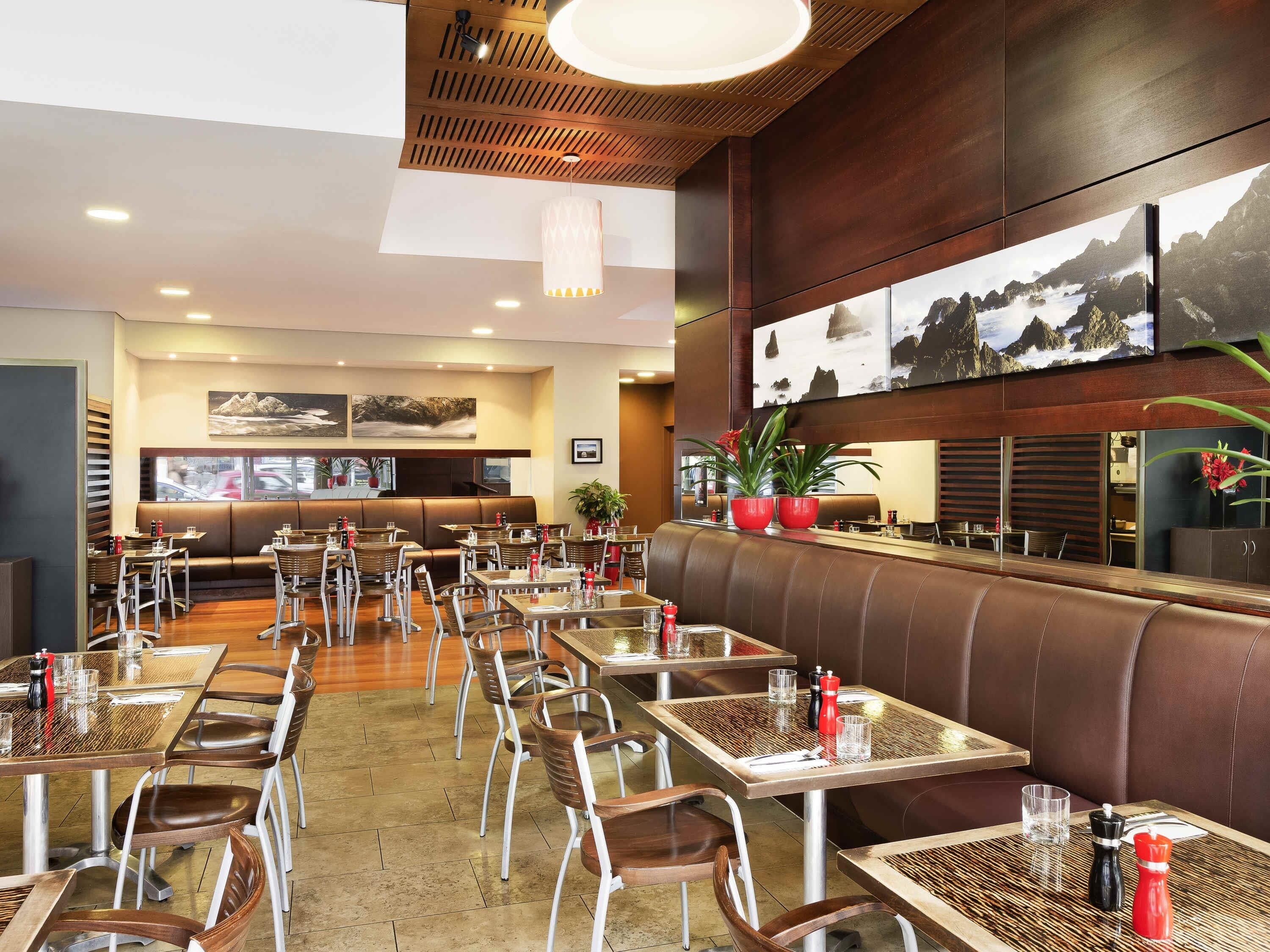 A restaurant with booths, tables, and chairs, featuring a wooden ceiling and wall art.