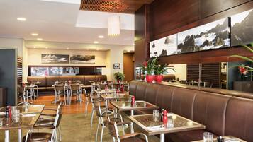 A restaurant with booths, tables, and chairs, featuring a wooden ceiling and wall art.