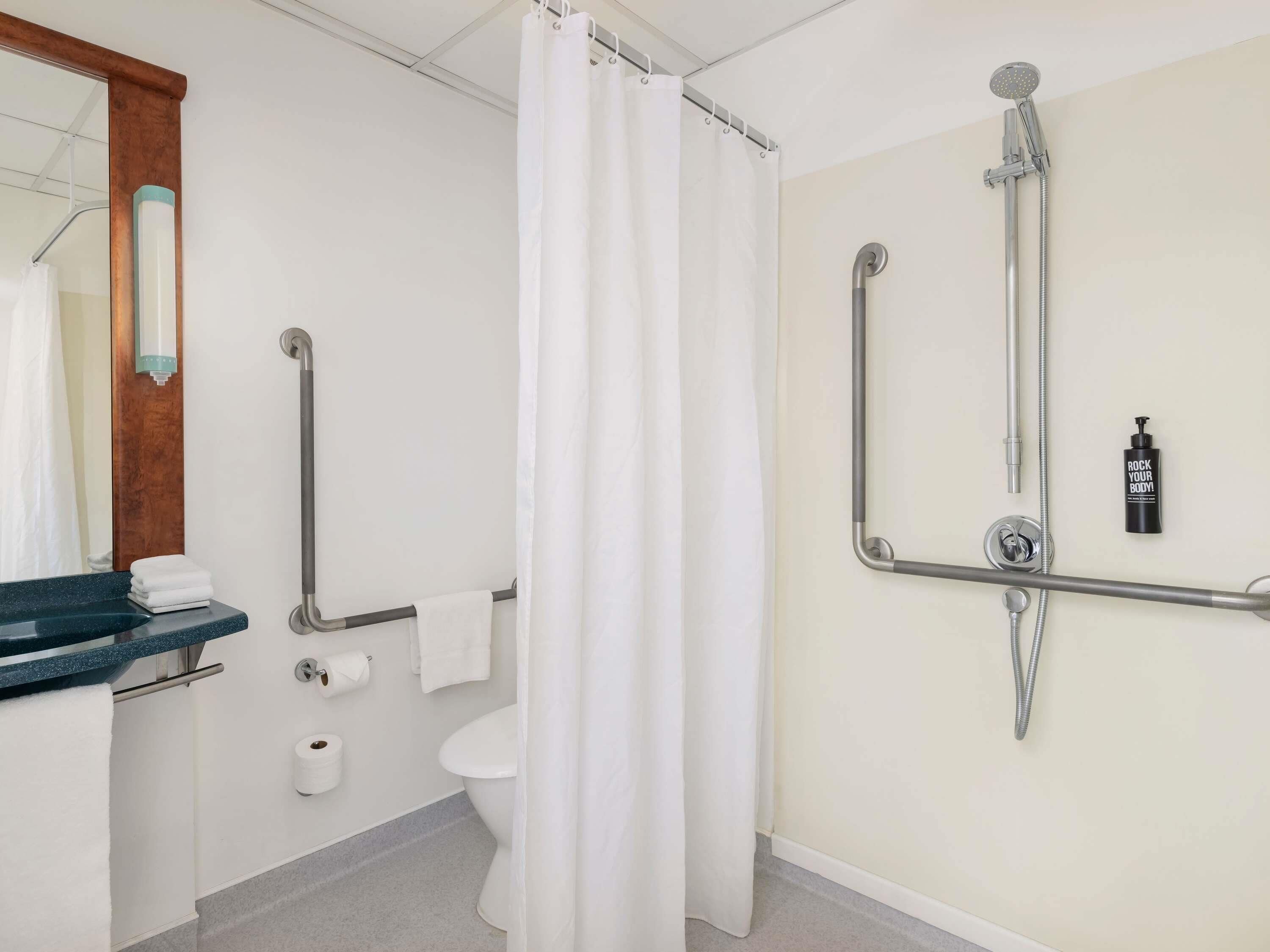 A bathroom with a shower, toilet, and a towel rack.
