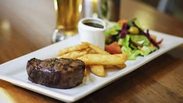 A plate with a steak, fries, and a salad on a table.